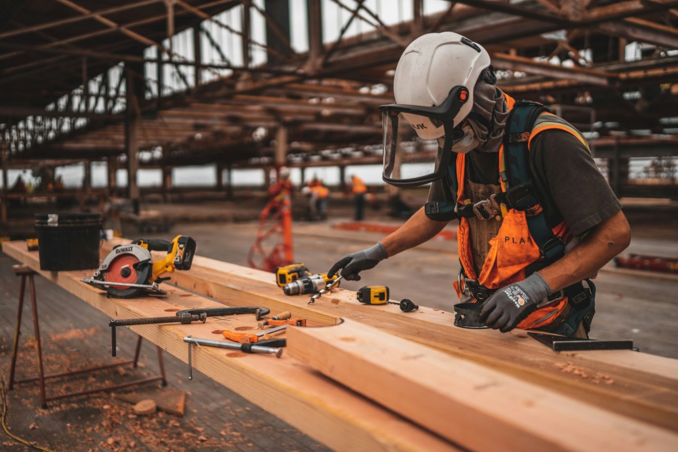 A man measures and cuts wood on a construction site