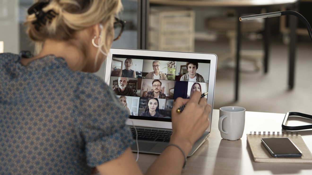 A woman participates in a video call with a group of coworkers