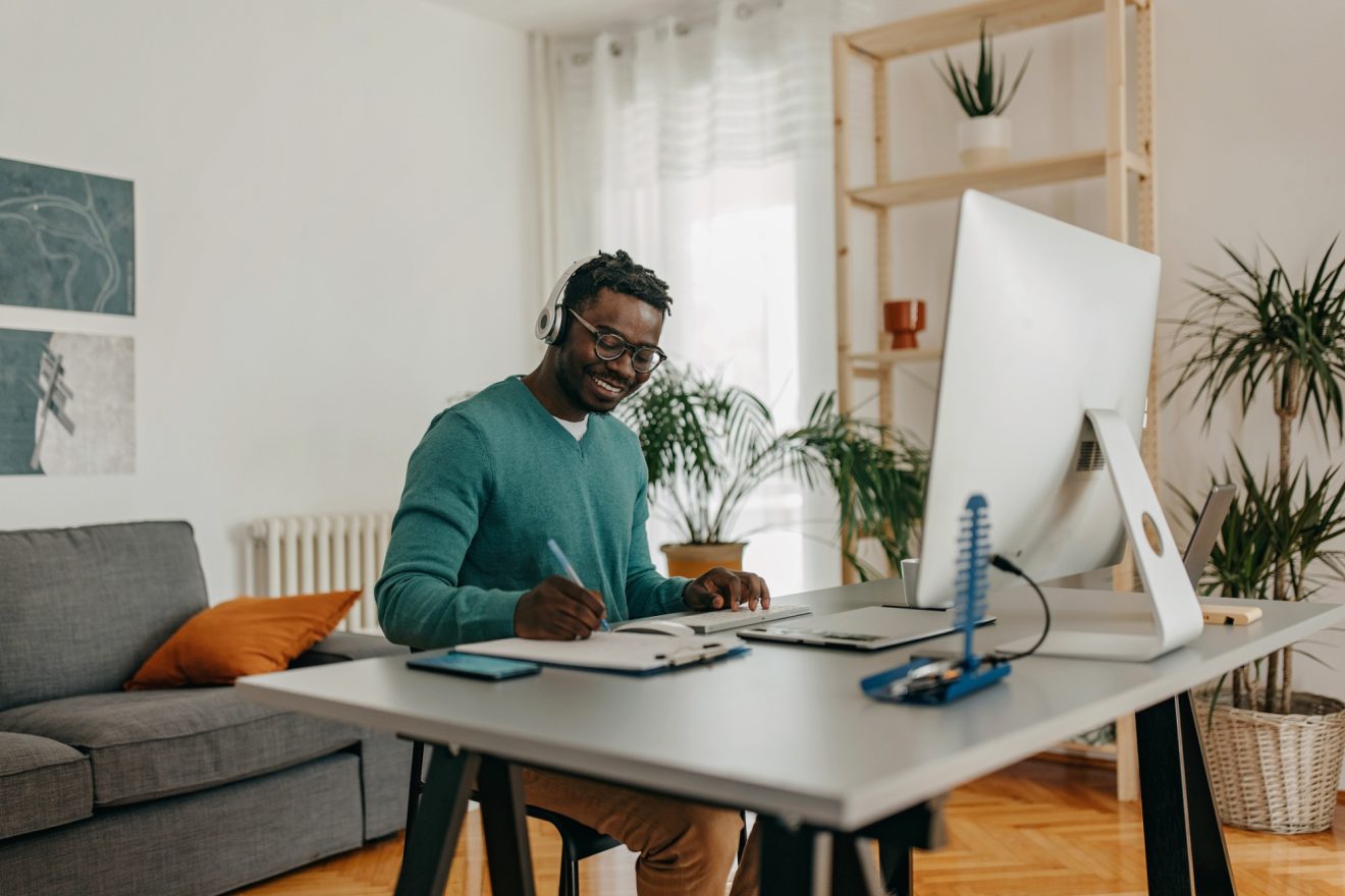 A man takes notes from a video call he is participating in