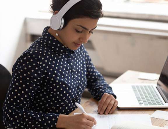 A woman takes notes in an online training class