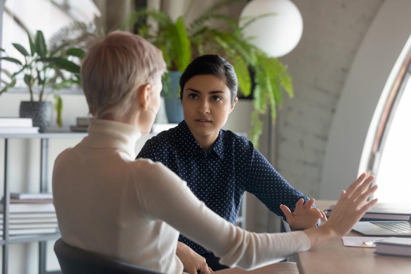 Two people talking at a desk